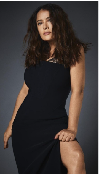 Salma Hayek in a black dress against a gray backdrop